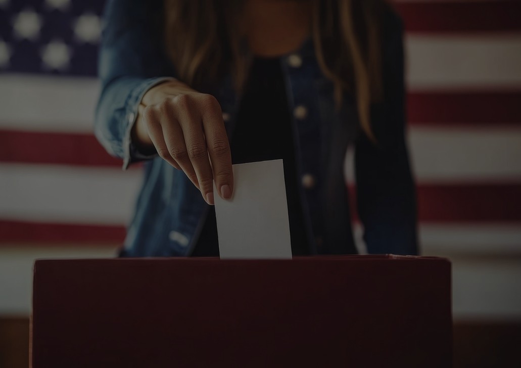 A voter drops a ballot in a box.
